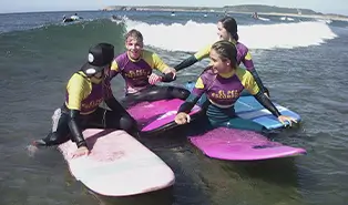 Campamento inglés: escuela de surf para aprender olas y corrientes en inglés Campamento inglés: niños practicando surf en la playa de Salinas con monitores titulados.