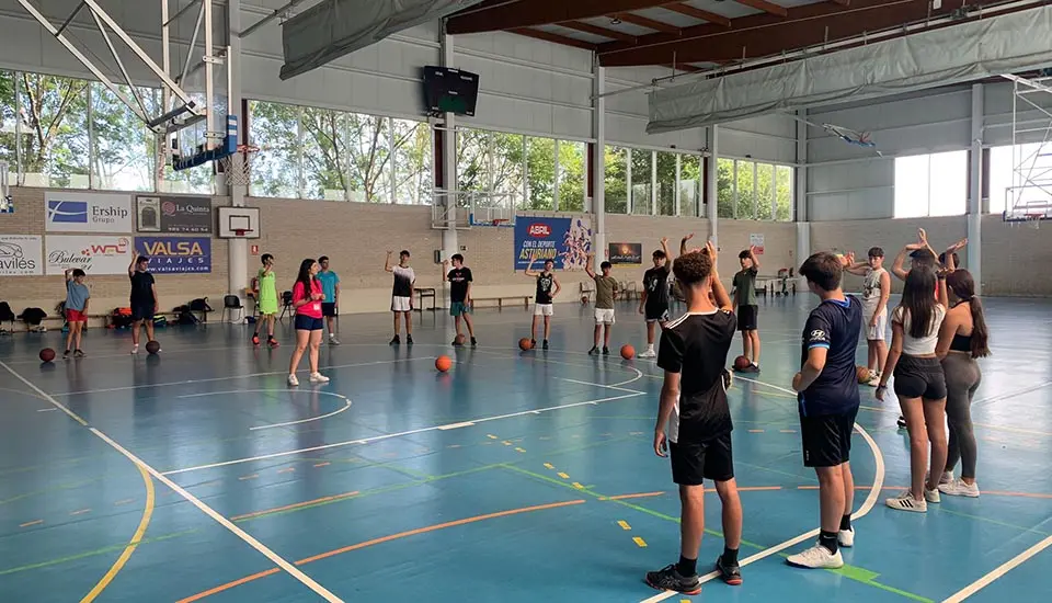 Jóvenes haciendo calentamiento de baloncesto con coaches internacionales en el campamento de verano