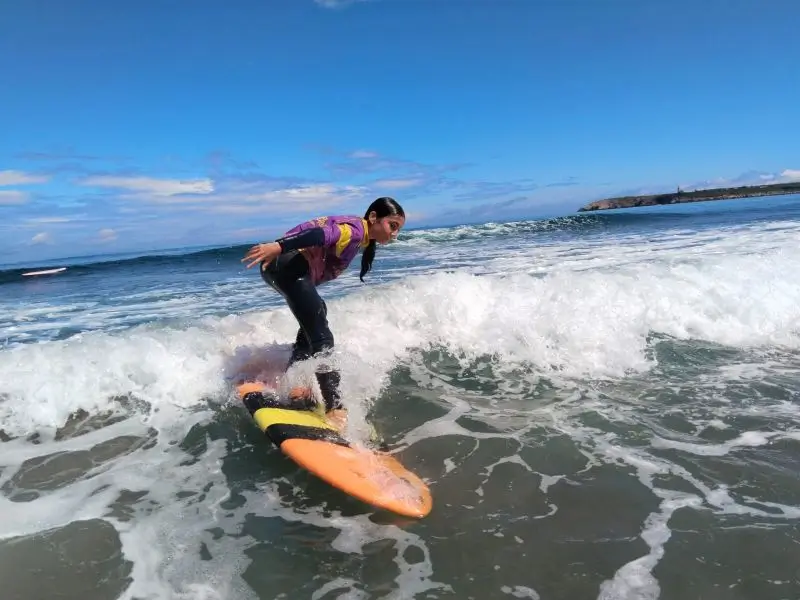 Niña en la actividad de Surf en la playa de Salinas durante el campamento de verano en inglés