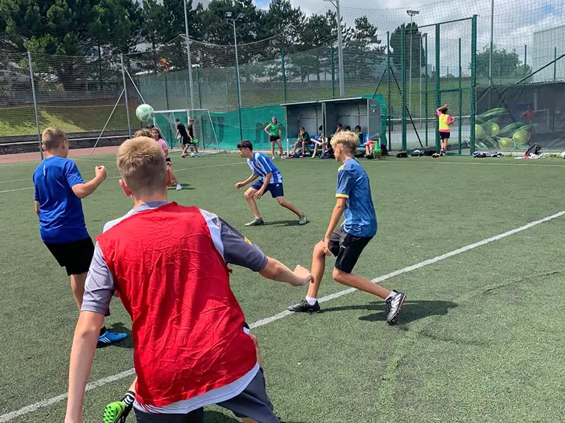 Grupo de jóvenes entrenando fútbol con coaches internacionales en el campamento de verano en inglés
