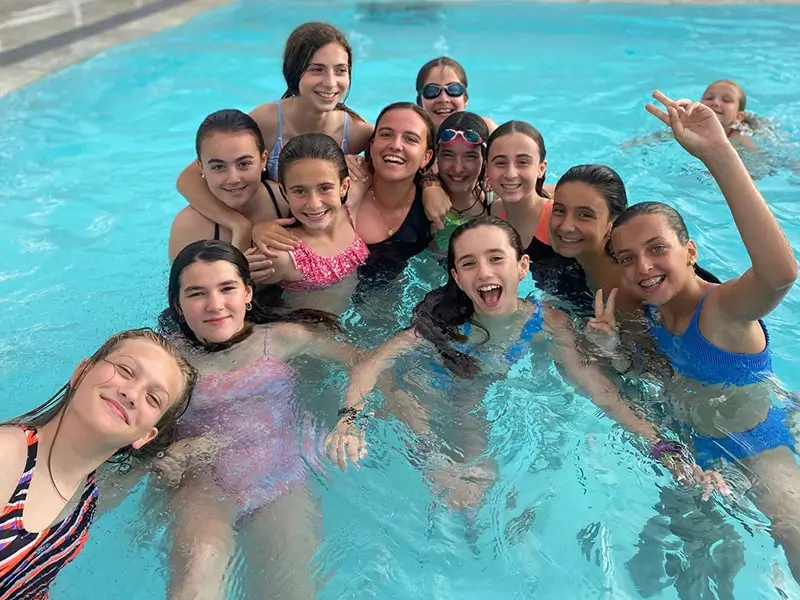 Grupo de jóvenes en una piscina con sus coaches internacionales en el campamento de verano en inglés