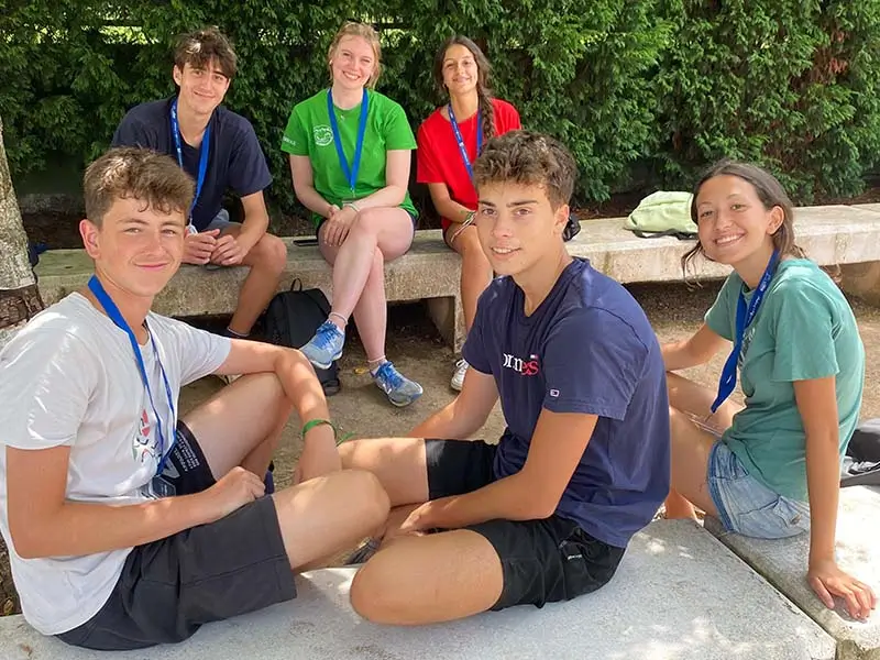 Grupo de cinco jóvenes conversan con su coach internacional en una sesión 1 to 5 del campamento inglés